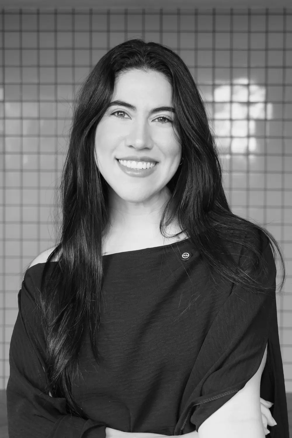 Priscila Vieira, sorrindo, de braços cruzados, em foto em preto e branco